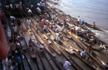 dugout;canoe;canoes;stack;stacked;pile;pile_up;person;people;crowd;crowded;trade;trading;trader;traders;buy;buying;sell;selling;produce;river